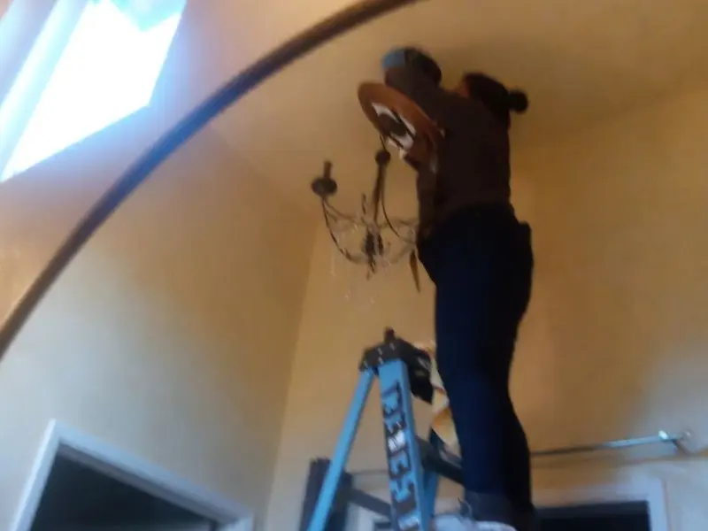 Electrician installing a chandelier in a Oakland residence